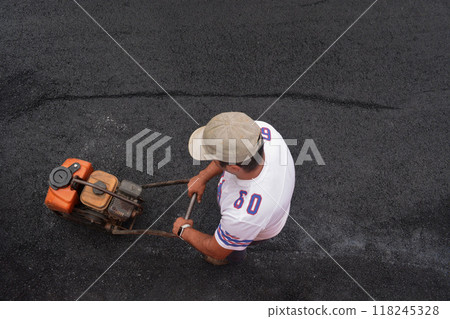 Porto, Portugal - 2024, September 1: Close-up of a worker operating a machine compacting asphalt on a fresh road. Concept of repair work in old historical cities, urban development technologies Porto, Portugal - 2024, September 1: Close-up of a worker operating a machine compacting asphalt on a fresh road. Concept of repair work in old historical cities, urban development technologies 118245328
