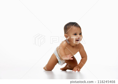 Little happy baby girl, toddler in diaper crawling cheerfully on bed isolated on white studio background. Exploring and playing 118245408