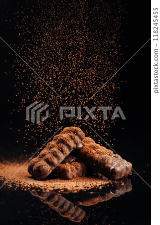 Chocolate bars with cocoa powder sprinkle on dark background, advertising and dessert concepts Chocolate bars with cocoa powder sprinkle on dark background, advertising and dessert concepts 118245455