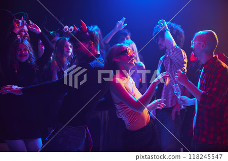 Group of young people, boys and girls in creative Halloween costumes enjoy night of festivities, dancing, laughing and drinking Group of young people, boys and girls in creative Halloween costumes enjoy night of festivities, dancing, laughing and drinking 118245547