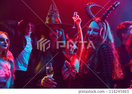 Young cheerful people, friends gathering at nightclub to celebrating Halloween, attending lively party, with costumes ranging from spooky to silly 118245803