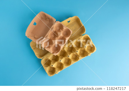 empty egg cartons stacked on a blue background, Ideal for recycling, storage solutions, packaging design discussions, recycling paper craft concept 118247217