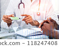 A doctor is holding a pill bottle and talking to a patient 118247408