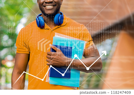 A man in an orange shirt is holding a stack of books and wearing headphones A man in an orange shirt is holding a stack of books and wearing headphones 118247409