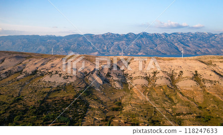 Blades of wind turbines rotate generating power on Pag Island at sunset twilight. Eco-friendly solution to convert wind into power on hill in Croatia 118247633