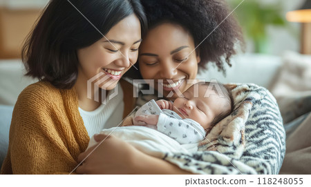 Two mothers holding their newborn baby at home 118248055
