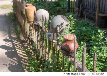 Rustic wicker fence with an old clay ceramic pots on it 118248484