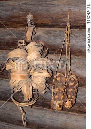 Woven bast shoes hang on the wall. Pairs of woven shoes 118248488