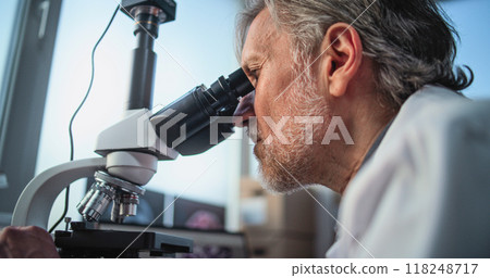 Close up of mature scientist analyzing fossil sample under microscope 118248717