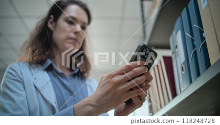 Close up of female scientist chatting on mobile phone in archaeological lab 118248728