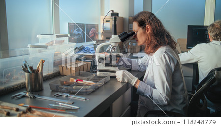 Female microbiologist conducts fossil analysis under microscope Female microbiologist conducts fossil analysis under microscope 118248779