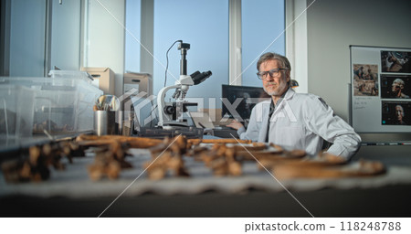 Mature scientist uses microscope, then examines fossil bones with magnifying glass 118248788