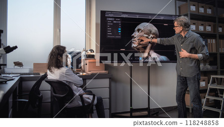 Male and female archaeologists work with 3D visualization of ancient human head anatomy Male and female archaeologists work with 3D visualization of ancient human head anatomy 118248858