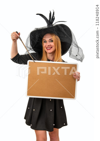 Smiling woman wearing a witch costume is holding a blank sign and pointing at it with a magic wand 118248914