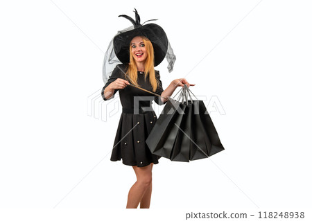 Excited witch holding shopping bags and a magic wand, conjuring up the best deals on a white background Excited witch holding shopping bags and a magic wand, conjuring up the best deals on a white background 118248938