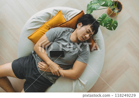 Man sleep over the phone on the bean bag sofa, taking a nap in the afternoon. Man sleep over the phone on the bean bag sofa, taking a nap in the afternoon. 118249229