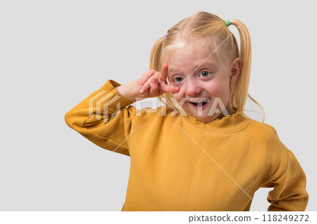Portrait of a cute little girl with blond hair making funny face over grey background 118249272