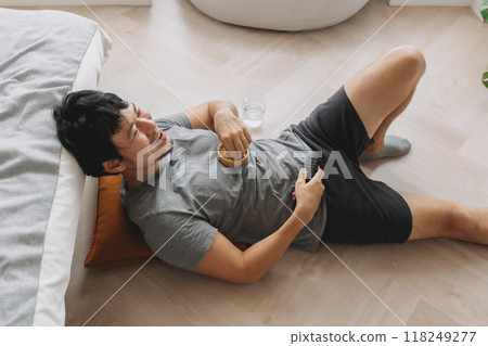 Man lying on the floor eating snack and laughing at the TV on weekends. Man lying on the floor eating snack and laughing at the TV on weekends. 118249277