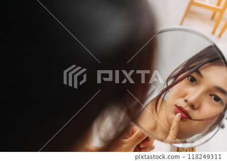 Woman using mirror for wearing make up. 118249311