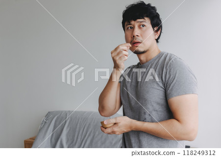 Man eating snacks peanuts in the house to increase his protein and magnesium. 118249312