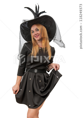 Attractive smiling blond woman in black witch hat and black dress. White background. Halloween costume party. Vertical frame Attractive smiling blond woman in black witch hat and black dress. White background. Halloween costume party. Vertical frame 118249373