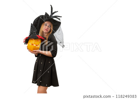 Dissatisfied attractive woman in black witch hat with jack o lantern in hands. Halloween costume party. White background. Copy space 118249383