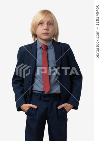 Portrait of a young serious boy in a suit stands and keeps hands in pockets. Isolated on white background. Portrait of a young serious boy in a suit stands and keeps hands in pockets. Isolated on white background. 118249450
