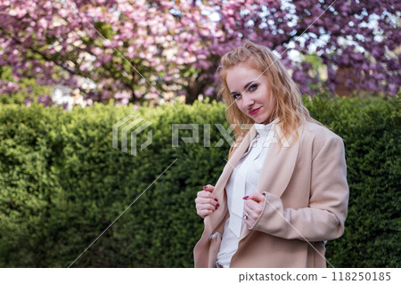 Modern woman in coat in spring park. Attractive serious young woman of European appearance. Successful business woman. 118250185