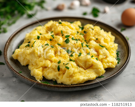 Close-up of a perfectly scrambled eggs dish, garnished with herbs on a plate.  118251913