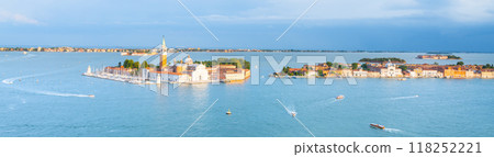 Visitors enjoy the scenic views of Saint George Island in Venice, Italy, amidst sparkling waters and vibrant surroundings during a bright, sunny day. 118252221