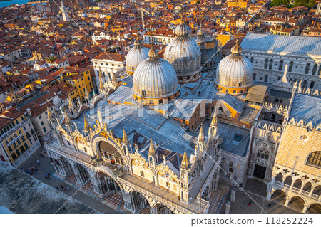 The stunning St Marks Basilica stands proudly in Piazza San Marco, showcasing its intricate architecture and domes against a vibrant sunset in Venice, attracting visitors and capturing hearts. 118252224