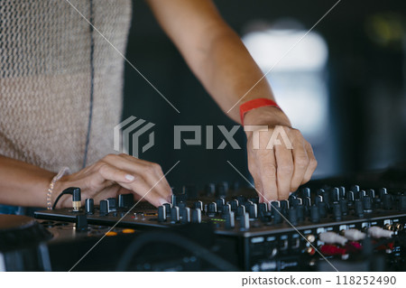 woman DJ Hands creating and regulating music on dj console mixer in a music festival woman DJ Hands creating and regulating music on dj console mixer in a music festival 118252490