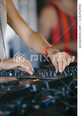 woman DJ Hands creating and regulating music on dj console mixer in a music festival 118252492