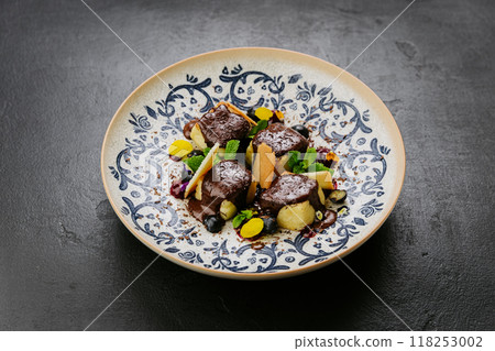 Chocolate-covered gourmet dessert with fresh mint, biscuit shards, and berries on a decorative plate 118253002