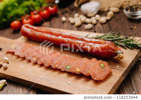 Sliced sausage with pistachios on wooden board, ideal for food presentations and gourmet displays Sliced sausage with pistachios on wooden board, ideal for food presentations and gourmet displays 118253044