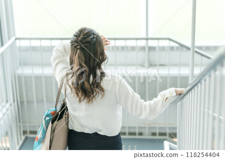 Young business woman in poor health going down the stairs (headache, fatigue, overwork) Young business woman in poor health going down the stairs (headache, fatigue, overwork) 118254404