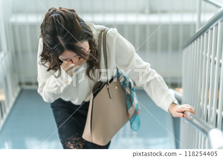 Business woman crouching down on the stairs due to unwellness (anemia, lightheadedness, dizziness) 118254405