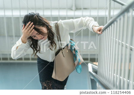 Business woman crouching down on the stairs due to unwellness (anemia, lightheadedness, dizziness) 118254406