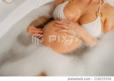 Expectant Mother Relaxing in Bathtub with Candles 118255356