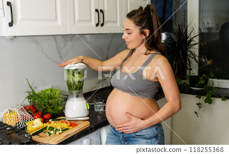 Young pregnant woman drinking healthy green smoothie at home. Young pregnant woman drinking healthy green smoothie at home. 118255368