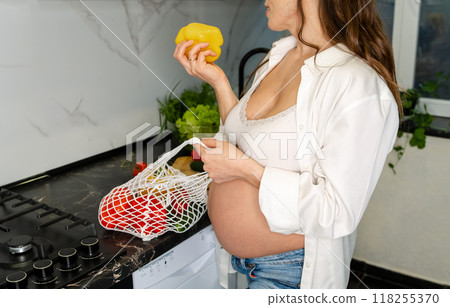 Pregnant Woman with Bell Pepper in Kitchen 118255370