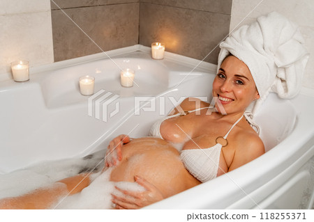 Pregnant Woman Relaxing in Bathtub with Candles 118255371