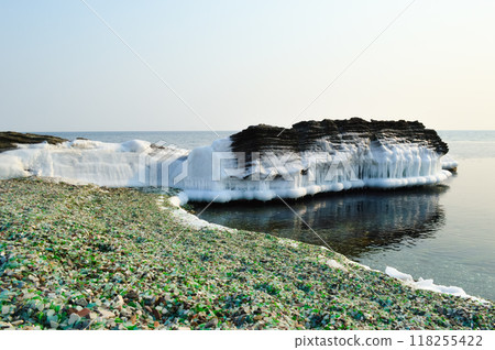 Multi-colored glass on the ice and snow of Japanese sea. Glass beach, Russia 118255422