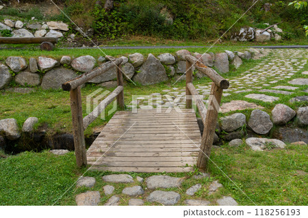 Rustic wooden bridge over small creek with stone pathway Rustic wooden bridge over small creek with stone pathway 118256193