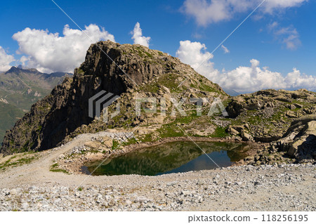 Small alpine lake reflecting rocky cliffs in a rugged mountain landscape 118256195