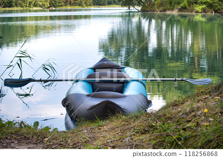 Tranquil scene of an inflatable kayak with a paddle on a lake shore Tranquil scene of an inflatable kayak with a paddle on a lake shore 118256868