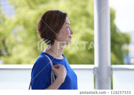 A female office worker's profile as she looks out the window, holding the strap of her bag at the train station. A female office worker's profile as she looks out the window, holding the strap of her bag at the train station. 118257333