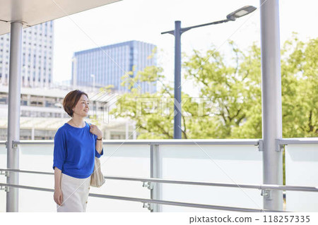 A businesswoman walks down a train station corridor with the city as a backdrop. A businesswoman walks down a train station corridor with the city as a backdrop. 118257335