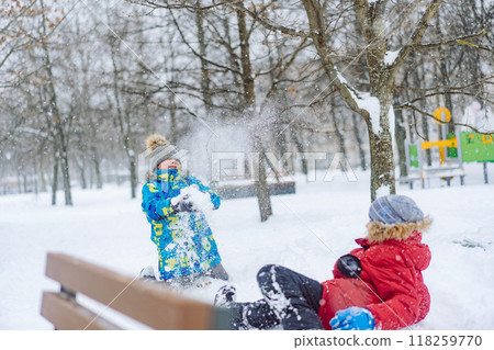 caucasian boys playing snowballs in park on sunny winter day caucasian boys playing snowballs in park on sunny winter day 118259770