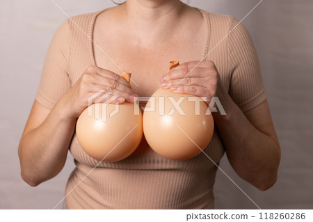a woman holding balloons in her hands symbolizes plastic surgery for breast augmentation a woman holding balloons in her hands symbolizes plastic surgery for breast augmentation 118260286